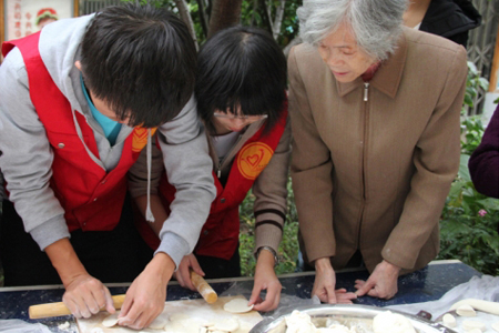 社区内一位老奶奶正在指点大学生擀饺子皮450.jpg