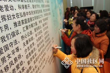 社区最美家庭代表在寻找“最美家庭”宣传牌上签字-（刘志-摄）.jpg