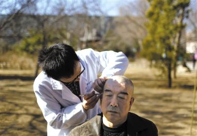 北京中医药大学耳针协会的学生为一社区老人贴耳针。昨天，朝阳区启动了“邻里守望”学雷锋志愿活动。新京报记者 韩萌 摄.jpg
