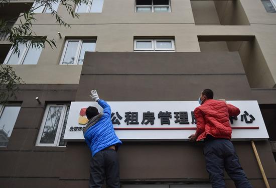 5工作人员在北京珠江东都国际项目的公租房外悬挂公租房管理服务中心的牌匾.jpg